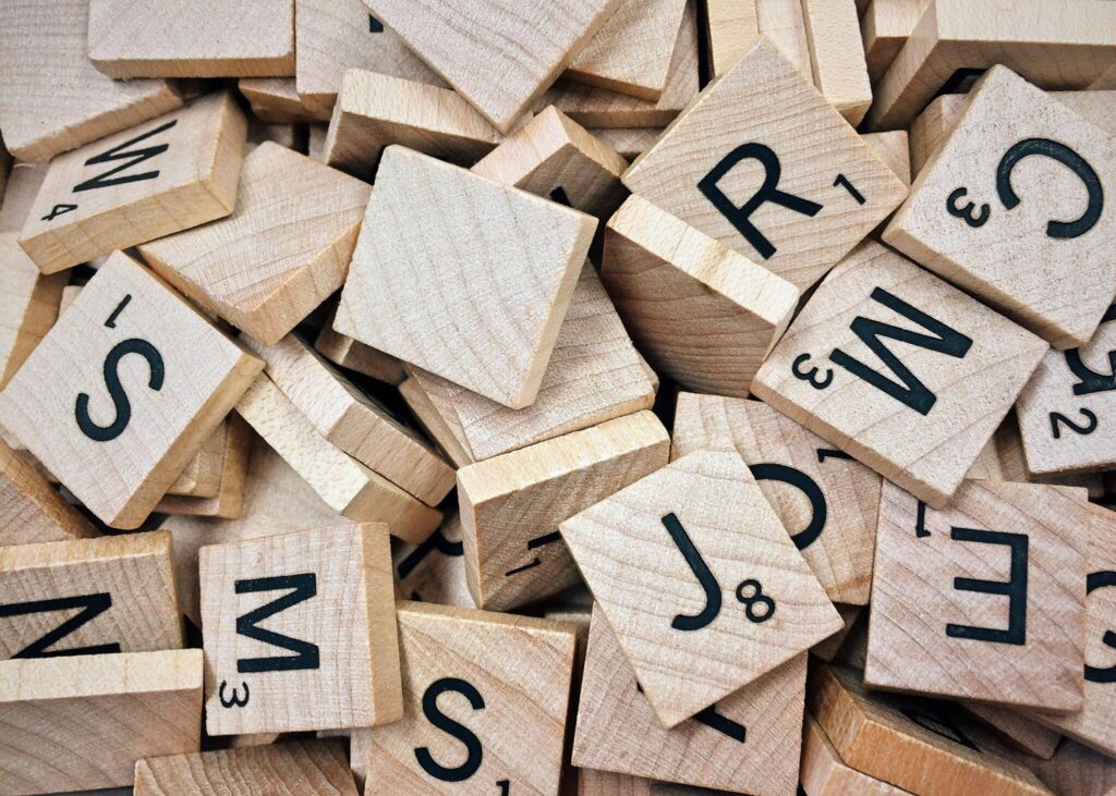 pexels-photo-278887-278887 A collection of wooden Scrabble tiles with letters and numbers stacked randomly.